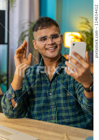 Happy Indian man taking selfie on smartphone communicating video call home online with subscribers Happy Indian man taking selfie on smartphone communicating video call home online with subscribers 114614412