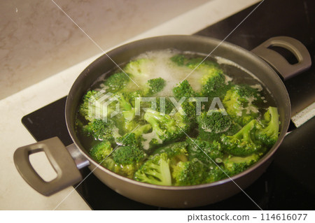 cooking broccoli in pan on electric stove cooking broccoli in pan on electric stove 114616077