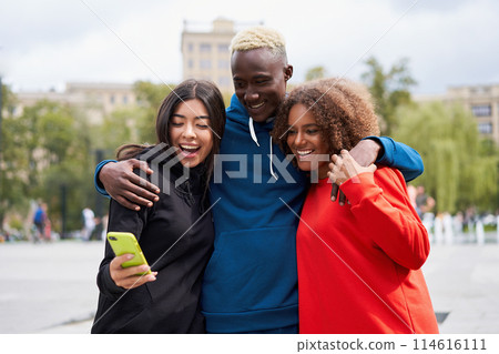 Happy diverse friends using smartphone in city Happy diverse friends using smartphone in city 114616111