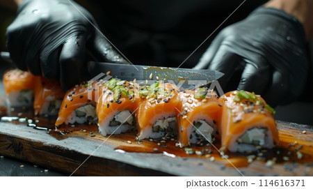 Closeup of chef's hands in black gloves slicing fresh sushi rolls 114616371