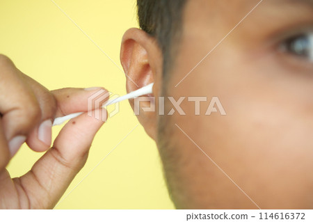 Closeup of young man using ear cotton bar 114616372