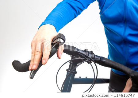 cyclist's hand on the brake lever of a bicycle steering wheel 114616747