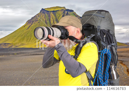 tourist photographer with a backpack photographs the beauty of nature in the mountains tourist photographer with a backpack photographs the beauty of nature in the mountains 114616783