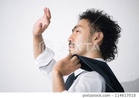 On a hot, scorching hot summer day, a man tries to block the dazzling sunlight as his suit starts to sweat. On a hot, scorching hot summer day, a man tries to block the dazzling sunlight as his suit starts to sweat. 114617018