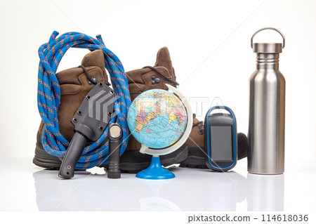 Items for tourism and hiking near trekking boots on a white background. Items for tourism and hiking near trekking boots on a white background. 114618036