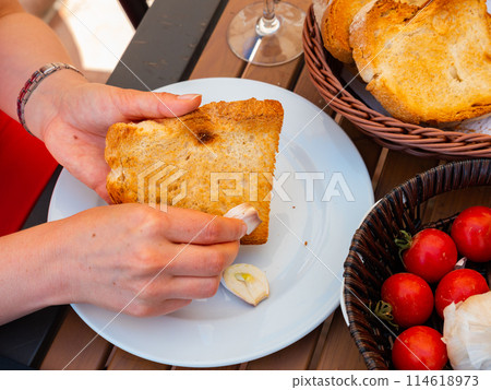 Female hands rubbing toast with garlic while preparing Pan Con Tomate 114618973