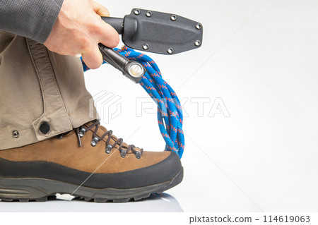 trekking boots for hiking next to a climbing rope and a knife on a white background 114619063