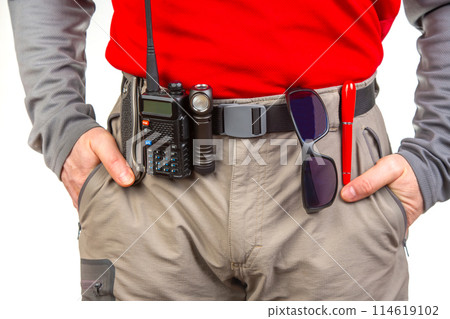 Pen, walkie-talkie, knife and flashlight with clips on the waistband of trekking pants. EDC items 114619102