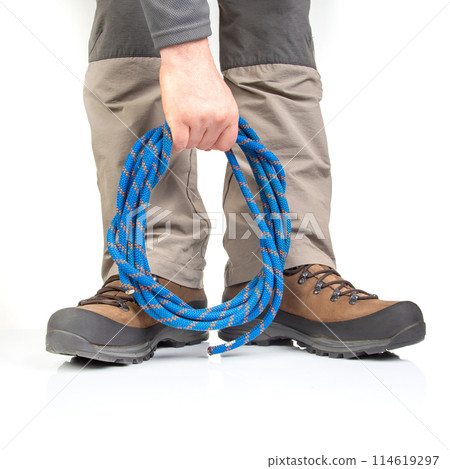 trekking boots for hiking next to a climbing rope on a white background. Travel and Hiking Equipment 114619297