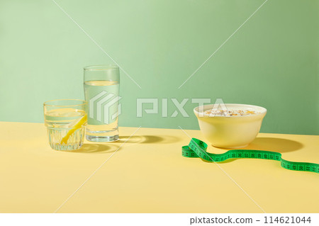 Creative template of weight losing concept, light yellow table contains healthy food and drink for dietary like lemonade and fruit yogurt. Vacant space in center for displaying product, copy space Creative template of weight losing concept, light yellow table contains healthy food and drink for dietary like lemonade and fruit yogurt. Vacant space in center for displaying product, copy space 114621044