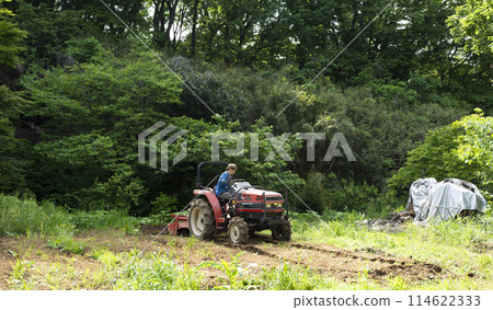 Young man plowing the field with a tractor 114622333