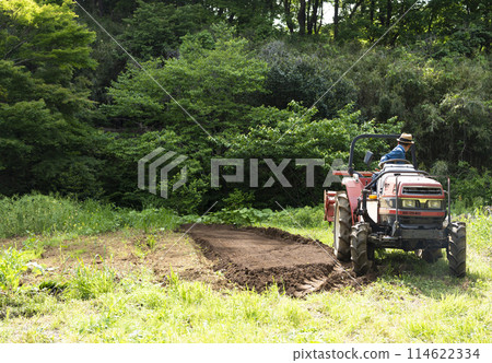 Young man plowing the field with a tractor 114622334