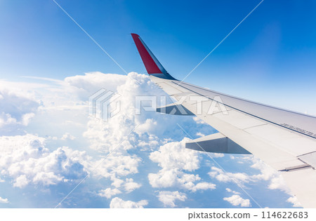 View from the airplane window at a beautiful cloudy sky and the airplane wing 114622683