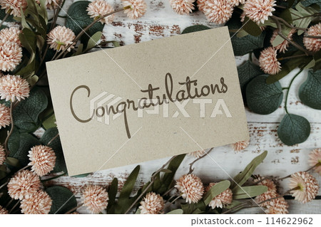 Congratulations text message on paper card with flowers border frame on wooden background 114622962