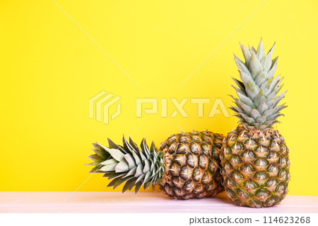 Two ripe pineapples on a yellow background Two ripe pineapples on a yellow background 114623268