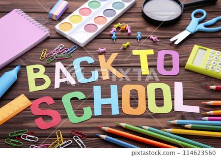 Inscription Back To School with school supplies on brown wooden background 114623560