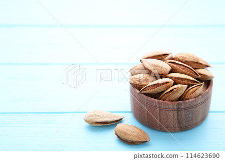 Wooden bowl of almonds on blue background 114623690