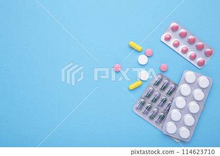 Colored pills and tablets in blister on a blue background, top view 114623710