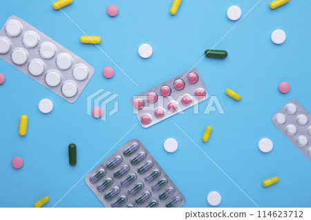 Colored pills and tablets in blister on a blue background, top view 114623712