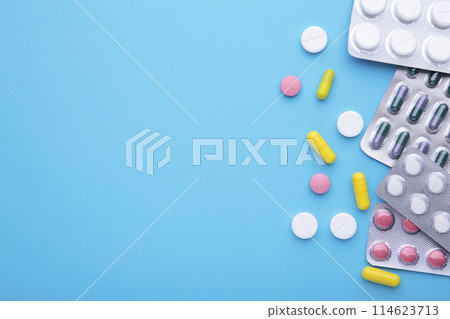 Colored pills and tablets in blister on a blue background, top view Colored pills and tablets in blister on a blue background, top view 114623713