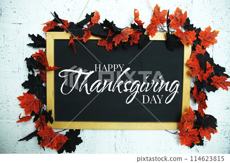 Happy Thanksgiving text message on Blackboard decoration with maple leaves hanging on a concrete wall background Happy Thanksgiving text message on Blackboard decoration with maple leaves hanging on a concrete wall background 114623815