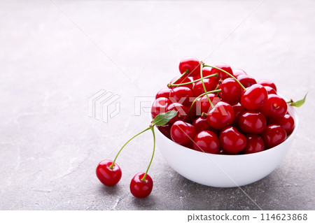 Fresh red cherry fruit in plate on grey concrete background Fresh red cherry fruit in plate on grey concrete background 114623868