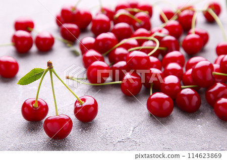 Fresh sweet cherries with leaves on grey concrete background, top view 114623869