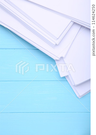 Stack white paper on blue wooden background with Clipping Path 114624250