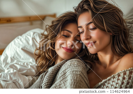 Couple of women laying on top of bed next to each other. Generative AI 114624964