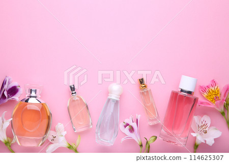 Perfume bottles with flowers on pink background, copy space 114625307