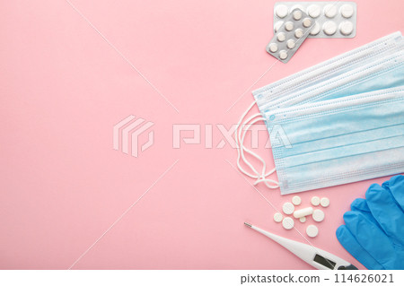 Medical thermometer and mask with pills on pink. Medical concept with copy space Medical thermometer and mask with pills on pink. Medical concept with copy space 114626021