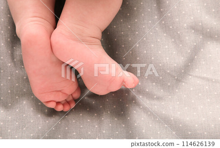 Small cute baby feet on grey bed 114626139