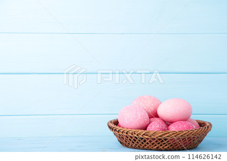 Pink easter eggs in basket on blue wooden background 114626142