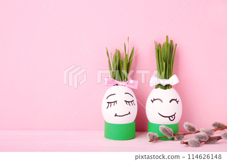 Cute handmade egg with hair of green grass with willow branches. Easter concept on pink background Cute handmade egg with hair of green grass with willow branches. Easter concept on pink background 114626148