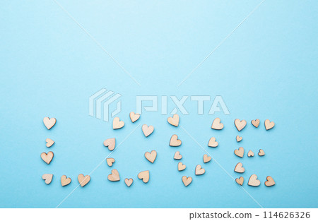 Many small wooden hearts on blue background. Backdrop for wedding cards or Valentine. Top view. Flat lay. 114626326