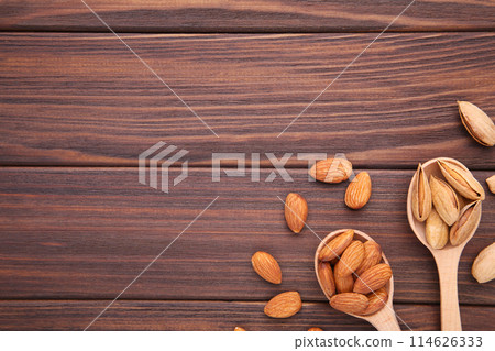 Almonds on wooden spoons on brown wooden background Almonds on wooden spoons on brown wooden background 114626333