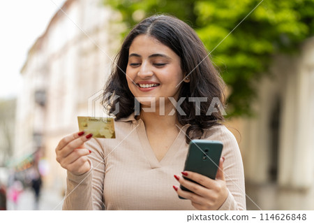 Indian woman using credit bank card smartphone while transferring money purchases online shopping 114626848