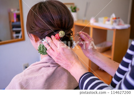 一位年輕女子在美容院將頭髮設計成與和服相配的後視圖 一位年輕女子在美容院將頭髮設計成與和服相配的後視圖 114627200