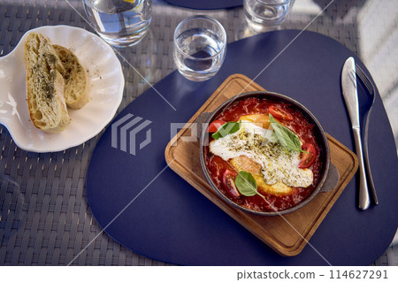 medium sized woman in peach fuzz dress eating Shakshouka in modern restaurant medium sized woman in peach fuzz dress eating Shakshouka in modern restaurant 114627291