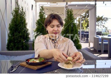 medium sized woman in peach fuzz dress eating Shakshouka in modern restaurant medium sized woman in peach fuzz dress eating Shakshouka in modern restaurant 114627299