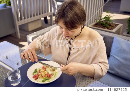 medium sized woman in peach fuzz dress eating cottage cheese pancakes with salmon and spinach in modern restaurant medium sized woman in peach fuzz dress eating cottage cheese pancakes with salmon and spinach in modern restaurant 114627325