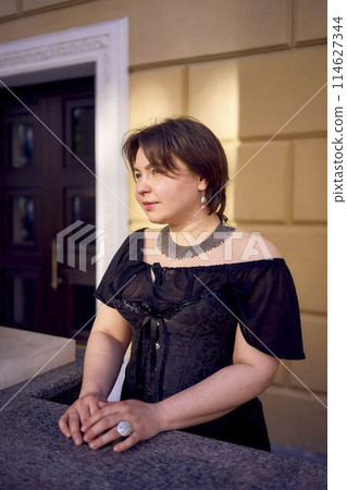 a medium-sized woman in a black corset near a theater with antique columns a medium-sized woman in a black corset near a theater with antique columns 114627344