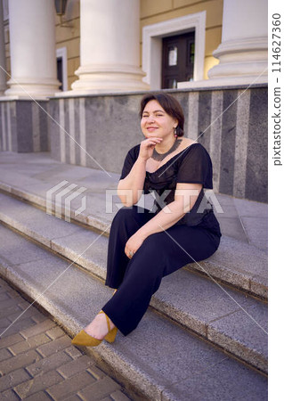 a medium-sized woman in a black corset near a theater with antique columns a medium-sized woman in a black corset near a theater with antique columns 114627360