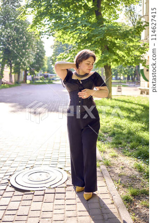 a medium size woman in a black corset and wide leg trousers walks through the city in the morning light a medium size woman in a black corset and wide leg trousers walks through the city in the morning light 114627415