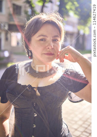 a    medium size woman in a black corset and wide leg trousers walks through the city in the morning light 114627419