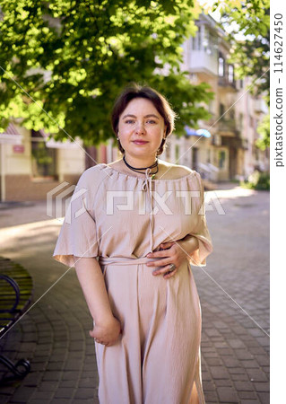 plus size woman in peach fuzz dress dancing on the streets of the morning city 114627450