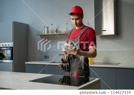 Professional Technician Repairing a Kitchen Stovetop in a Modern Home During Daytime Professional Technician Repairing a Kitchen Stovetop in a Modern Home During Daytime 114627534
