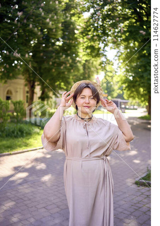 plus size woman in peach fuzz dress with hat having fun on morning city streets 114627774