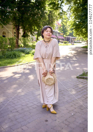 plus size woman in peach fuzz dress with hat having fun on morning city streets plus size woman in peach fuzz dress with hat having fun on morning city streets 114627777