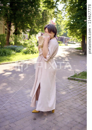 plus size woman in peach fuzz dress with hat having fun on morning city streets plus size woman in peach fuzz dress with hat having fun on morning city streets 114627778